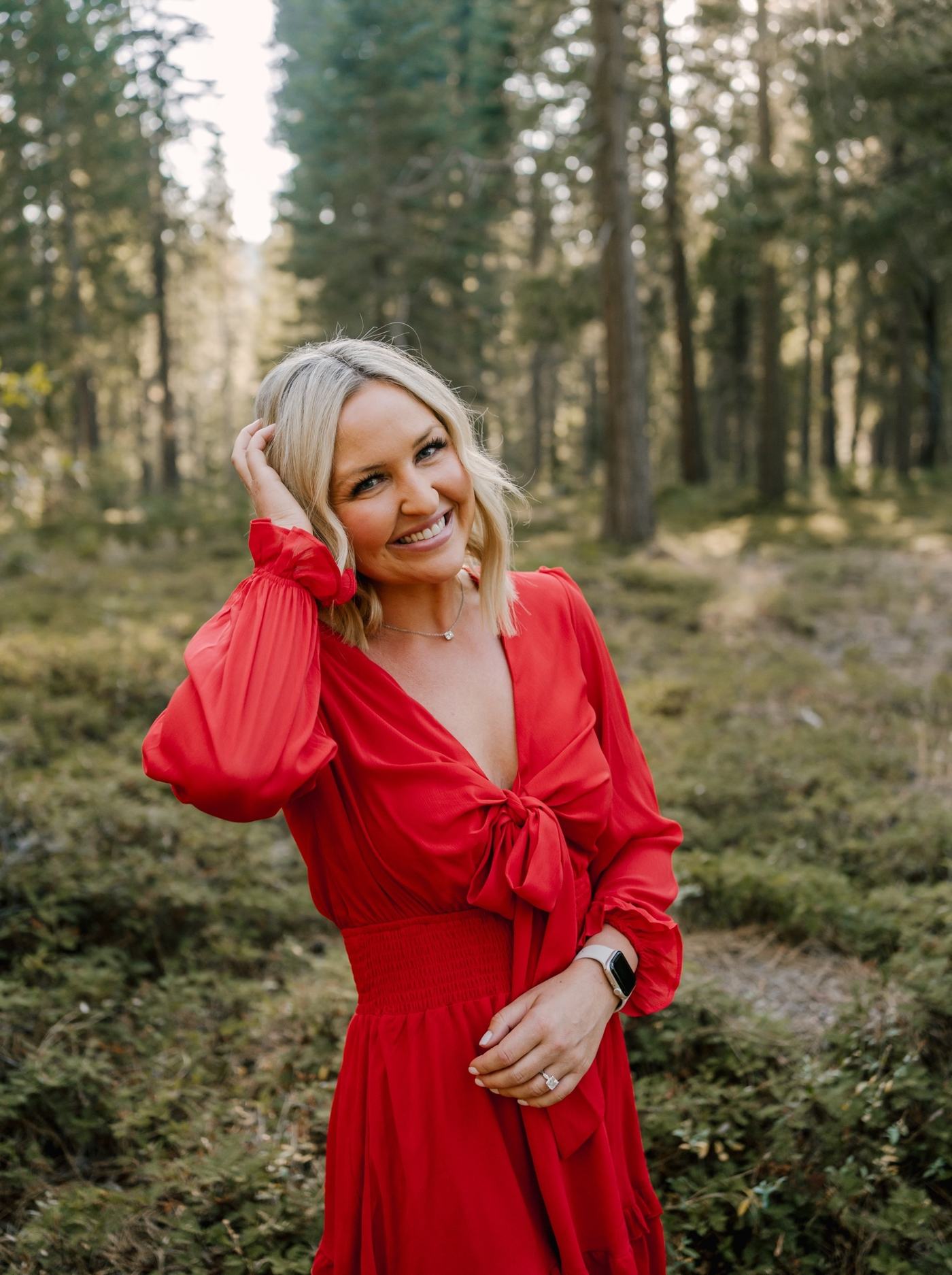 Adele in a red dress in the forest, smiling